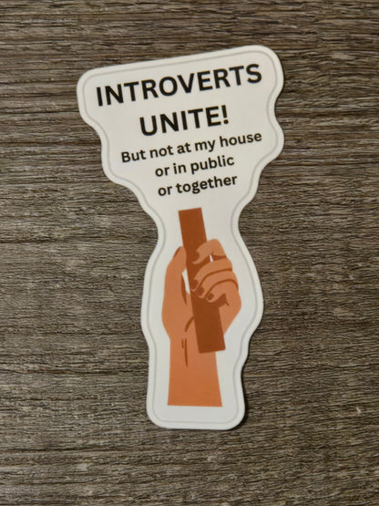 A sticker with the text "INTROverts UNITE!" and an illustration of a hand holding a stick.